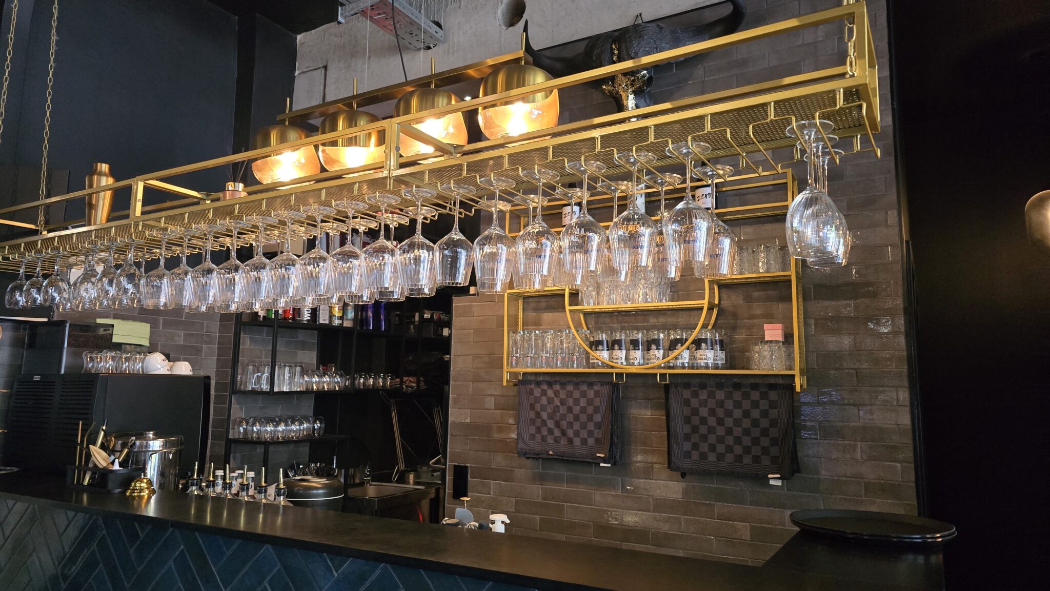 Die beleuchtete Bar mit hängenden Gläsern, der perfekte Ort für Drinks auf Ihrer privaten Feier in Bremen.